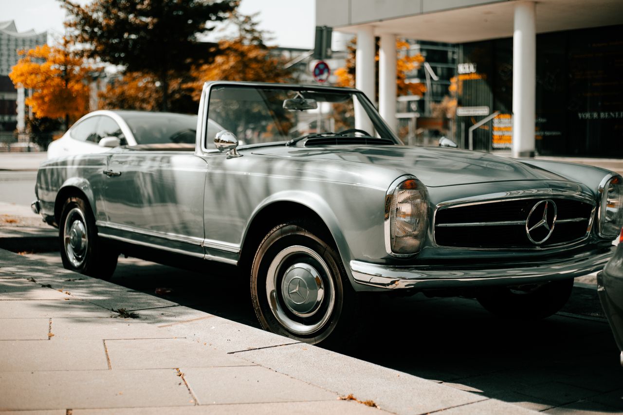 Elegant classic Mercedes-Benz parked on city street in autumn setting.