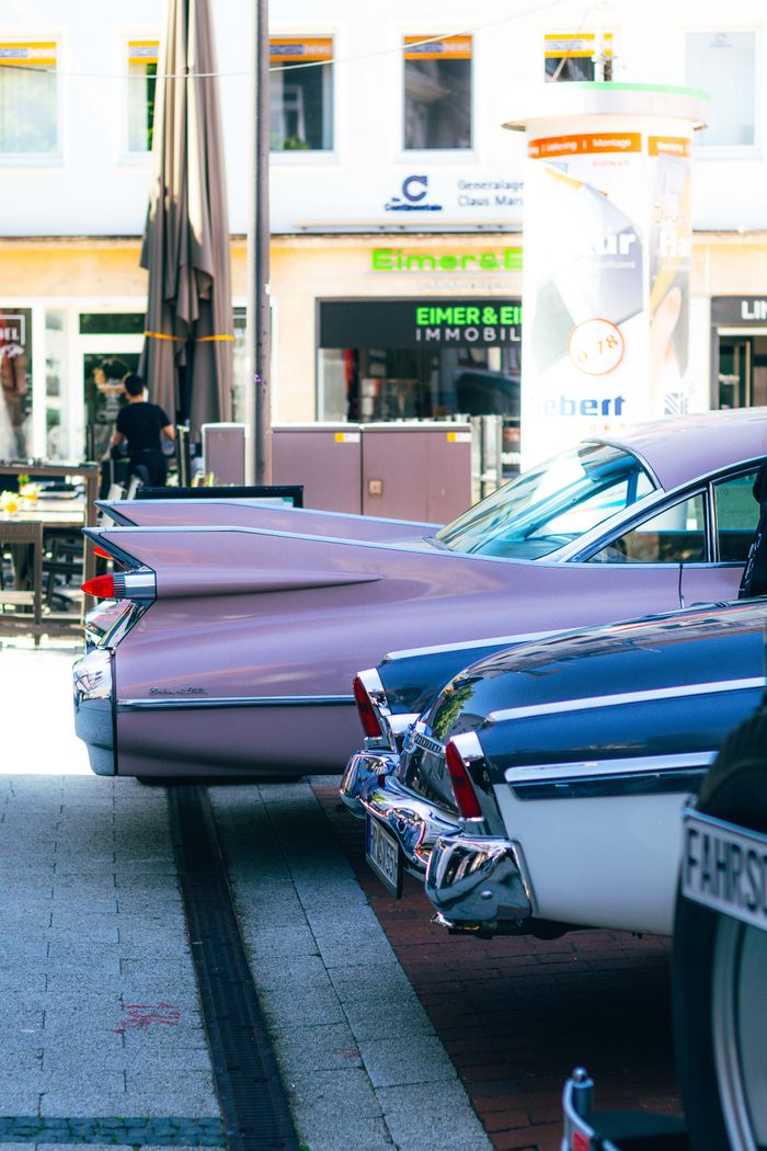 Vintage cars displayed outdoors at a vibrant summer car meet, showcasing sleek designs.